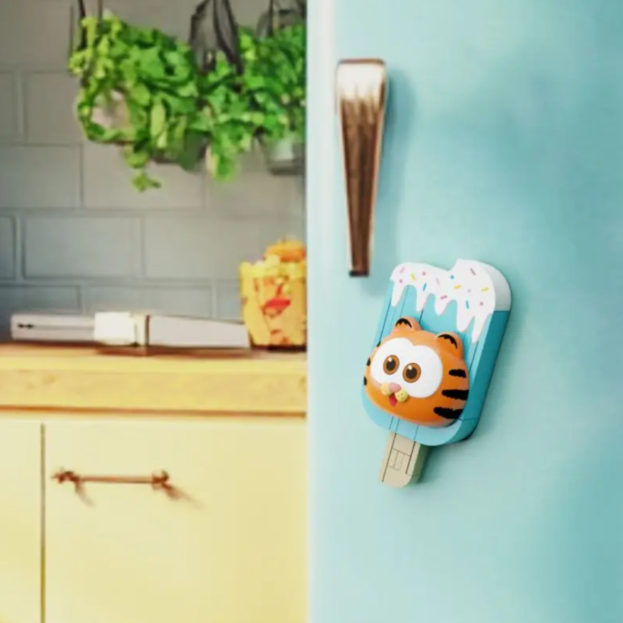 Fridge magnet shaped like a tiger on an ice cream stick attached to a refrigerator.