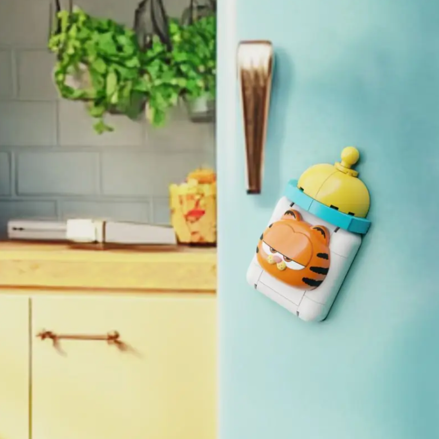 Fridge magnet shaped like a cartoon tiger with a yellow hat on a light blue refrigerator.